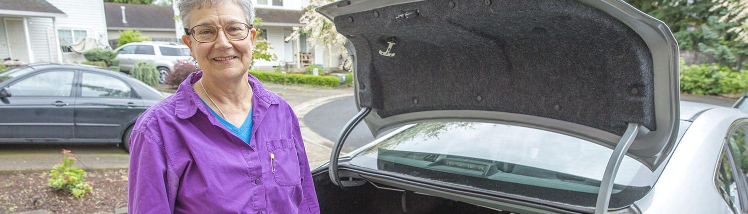 Personal Support Worker unloading groceries from the trunk of her car