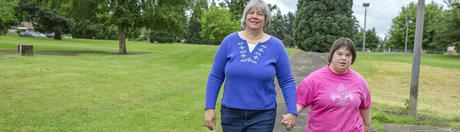 Homecare worker walking and holding hands with her daughter who is also her client